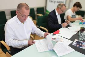Pokaż zdjęcie: Dwóch mężczyzn i jedna kobieta - przedstawiciele Powaitu Dąbrowskiego podpisują dokumenty
