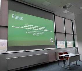 Pokaż zdjęcie: W Sali konferencyjnej, na ekranie wyświetlana jest prezentacja.