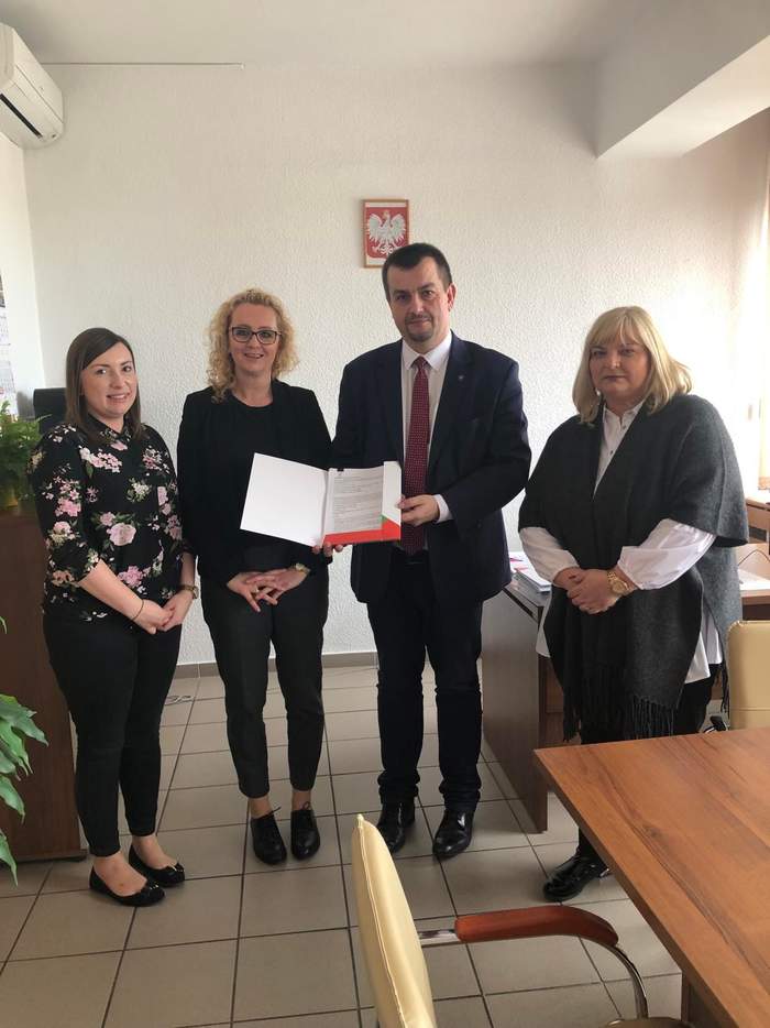 Pokaż zdjęcie: Dyrektor Oddziału Lubuskiego PFRON wraz z przedstawicielami Stowarzyszenia na Rzecz Osób z Autyzmem stoją razem w Gabinecie Dyrektora, a Dyrektor trzyma w ręku umowę
