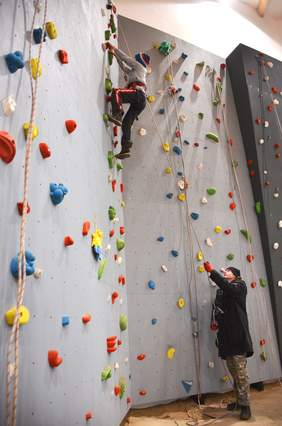 Na ściance wspinaczkowej - wspinające sie dziecko i osoba asekurująca