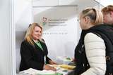 Stoisko Państwowego Funduszu Rehabilitacji Osób Niepełnosprawnych. Kobieta za ladą rozmawia z uczestniczką targów i przekazuje materiały informacyjne.