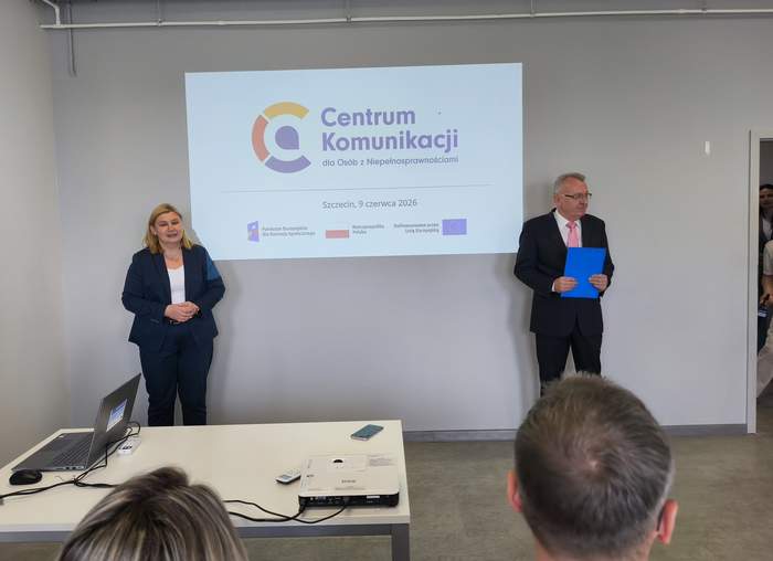 Oficjalne spotkanie w sali konferencyjnej na tle ekranu projekcyjnego z logo i napisem "Centrum Komunikacji dla Osób z Niepełnosprawnościami, Szczecin 9 czerwca 2026". Po lewej kobieta z w ciemnym garniturze ze złożonymi przed sobą rękoma. Po prawej mężczyzna w garniturze i okularach. 