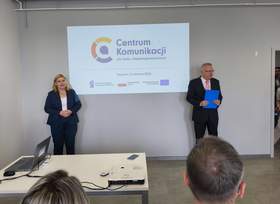 Oficjalne spotkanie w sali konferencyjnej na tle ekranu projekcyjnego z logo i napisem "Centrum Komunikacji dla Osób z Niepełnosprawnościami, Szczecin 9 czerwca 2026". Po lewej kobieta z w ciemnym garniturze ze złożonymi przed sobą rękoma. Po prawej mężczyzna w garniturze i okularach. 