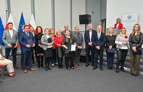 Grupa osób, kobiety i mężczyźni, stoją z dyplomami w rękach