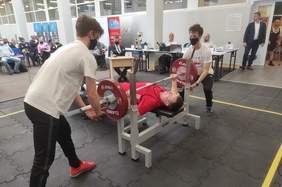 Pokaż zdjęcie: Zawodnik podnoszący sztangę w trakcie mistrzostw w otoczeniu sędziów