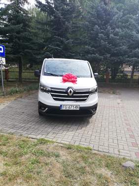 Pokaż zdjęcie: Bus w kolorze białym owinięty wstęgą na podwórku