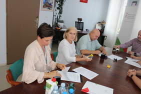 Pokaż zdjęcie: Przy stole konferencyjnym na którym leżą umowy, siedzą dwie kobiety i mężczyzna. 