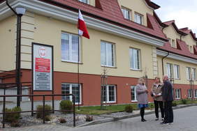 Pokaż zdjęcie: Trzy osoby, dwie kobiety i jeden mężczyzna stoją przed budynkiem i rozmawiają