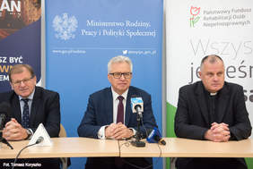 Pokaż zdjęcie: Trzech mężczyzn siedzących za stołem konferencyjnym odpowiada na pytania dziennikarzy