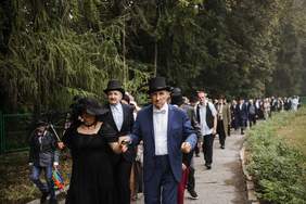 Pokaż zdjęcie: Duża liczba par ubranych w dziewiętnastowieczne stroje, kroczy w rytm poloneza.