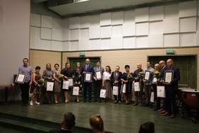 Pokaż zdjęcie: Zdjęcie przedstawia zieloną scene na której stoją wszyscy laureaci regionalnej gali Lodołamaczy. Za osobami ściana wyklejona jasna tapetą oraz dwoje zielonych drzwi.