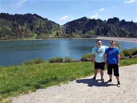 Pokaż zdjęcie: Dwóch uczestników ŚDS stoi nad Zalewem Czorsztyn, w tle widać tamę