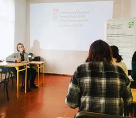 Pracownik Kujawsko-Pomorskiego Oddziału PFRON - Anna Wankiewicz - Lewandowska - podczas prelekcji, w tle ekran, a na nim wyświetlony slajd z prezentacji