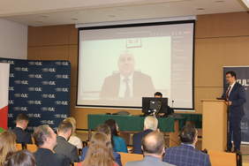 Pokaż zdjęcie: Zdjęcie auli, z sali widać ekran z połączeniem online z pełnomocnikiem rządu Pawłem Wdówikiem,