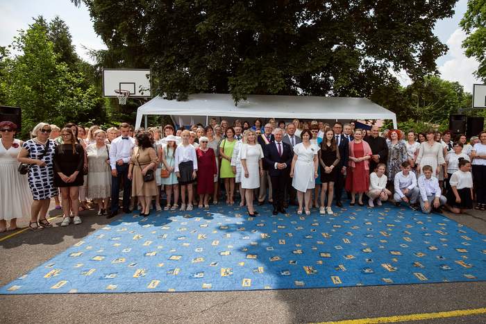 Pokaż zdjęcie: Pamiątkowa fotografia, na tle namiotów stoi grupa ok. 50 osób pozując do pamiątkowego zdjęcia.