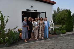 Pokaż zdjęcie: Przed wejściem do świetlicy pozuje do zdjęcia osiem kobiet.