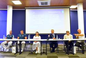 Pokaż zdjęcie: 6 osób siedzących przy stole przed mikrofonami