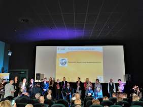 Grupa osób sytojących na scenie