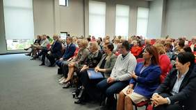 uczestnicy Dnia Seniora słuchają prelekcji, siedząc na sali