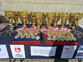 Pokaż zdjęcie: Stół na którym stoją puchary i leżą medale.