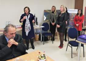 Dyrektor Oddziału Kujawsko-Pomorskiego PFRON Aleksandra Gierej stoi na środku z mikrfonem w dłoni, przemawia, po jej lewej stronie (po prawej na zdjęciu) stoi Prezes PZN Okręgu Kujawsko-Pomorskiego Izabela Wasilewska, a za nią jeszcze trzy kobiety, na pierwszym panie, przy stole siedzi mężczyzna, ze splecionymi dłońmy