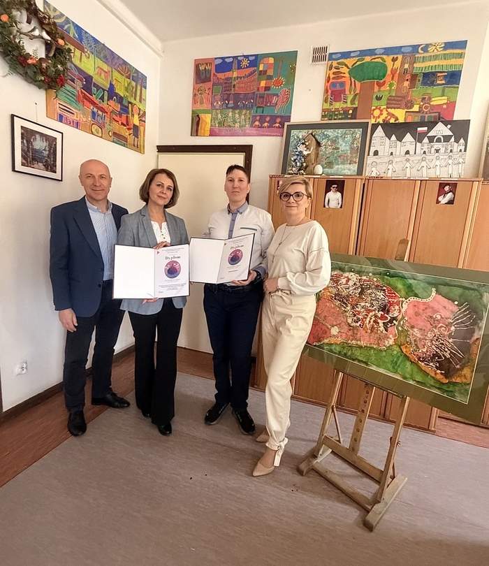 Pokaż zdjęcie: Edyta Kondzior, Krzysztof Drapczuk oraz pracownicy ośrodka prezentują dyplomy i nagrodzoną pracę plastyczną podczas spotkania w placówce.