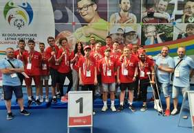 Pokaż zdjęcie: Drużyna zawodników na 1 miejscu podium z medalami na szyi 