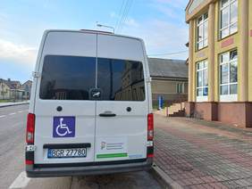 Pokaż zdjęcie: Tył autobusu na drzwiach logo PFRON i znak osoby na wózku inwalidzkim