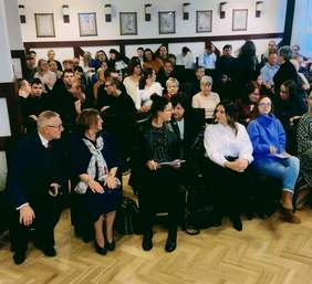 Zaproszeni goście i uczestnicy konferencji siedzą na krzesłach