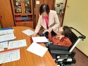 Pokaż zdjęcie: Osoba z niepełnosprawnością podpisuje umowę 