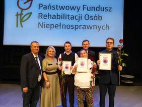 Pokaż zdjęcie: Nagrodzeni laureaci, w tym na wózku, stoją obok siebie na pamiątkowym zdjęcie, a wraz z nimi Dyrektor Oddzialu PFRON i Wicewojeoda Lubuski