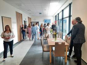 Pokaż zdjęcie: W pomieszczeniu znajduje się dużo osób. Zwiedzają i oglądają nowo otwarte Centrum Opiekuńczo-Mieszkalne w Zgierzu.  