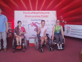 Pokaż zdjęcie: Zawodniczki na podium, w tym 2 na wózkach inwaldzkich na tle ścianki Mistrzostw