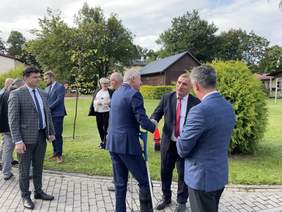 Pokaż zdjęcie: Dyrektor Oddziału Gratuluje Staroście sukcesu związanego z realizacją umowy. Obok stoją mężczyźni również ubrani w garniturach. Wszyscy są uśmiechnięci.