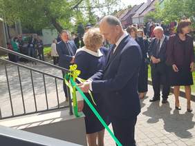 Mężczyzna przecina wstęgę, za nim licznie zebrani ludzie