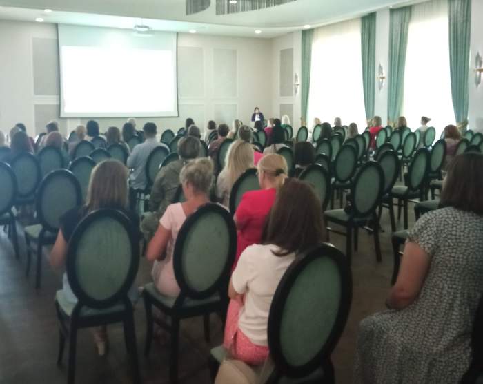 Pokaż zdjęcie: Zdjęcie z tyłu sali konferencyjnej w kierunku prelegenta.