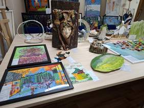 Na stołach rozłożone prace konkursowe: rzeźby i płaskorzeźby.