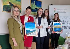 Pokaż zdjęcie: Pięć kobiet pozuje do zdjęcia. W rękach trzymają obrazy namalowane przez podopiecznych Stowarzyszenia