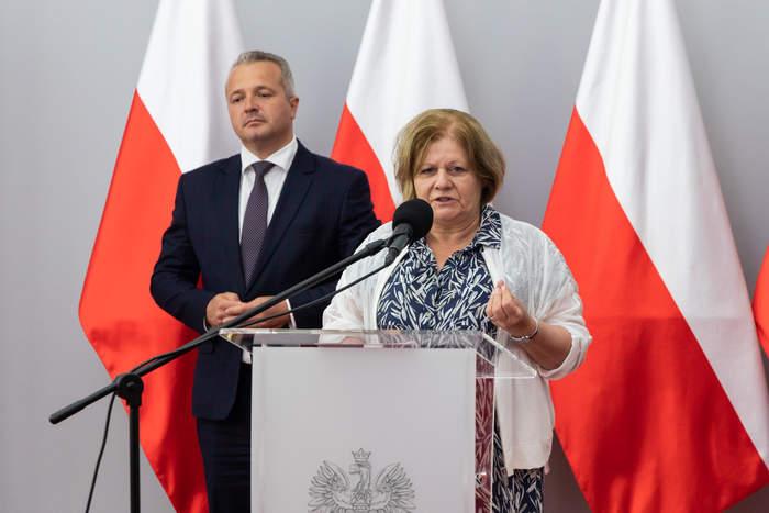 Dyrektor Aleksandra Gierej podczas przemówienia, a za nią, od lewej - Wojewoda Mikołaj Bogdanowicz oraz trzy flagi państwowe