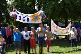 Pokaż zdjęcie: Na trawie stoją osoby i trzymają transparenty z hasłami WTZ Kock oraz czy wygramy czy przegramy zawsze dobry humor mamy