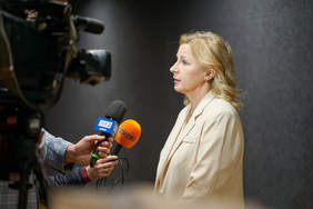 Pokaż zdjęcie: Wywiadu udziela kobieta blondynka w białej marynarce.