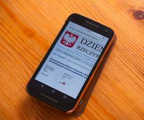 na telefonie komórkowym wyświetlone przykąłdowe rozporządzenie z widocznym godłem Polski i częścią nazwy Dziennik Ustaw