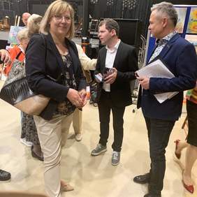 Pokaż zdjęcie: Mężczyźni i kobiety rozmawiają podczas wystawy obrazów na otwarciu Festiwalu w Bochni