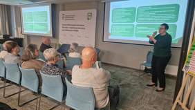 Pokaż zdjęcie: Tłumacz języka migowe tłumaczy prelekcję osobom na sali