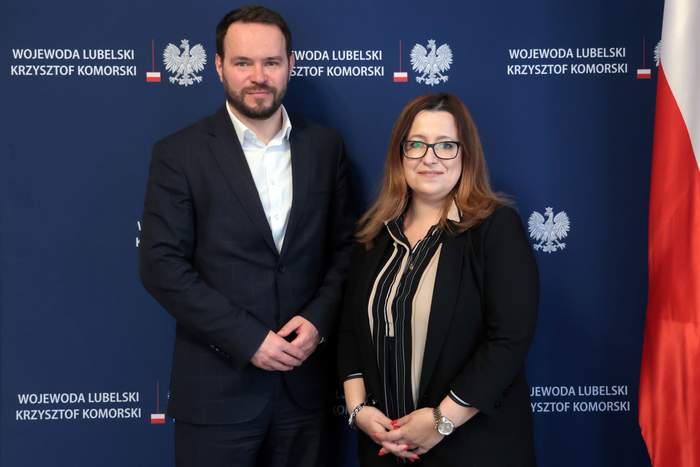 Pokaż zdjęcie: Na granatowym tle pozują do zdjęcia dwie osoby.