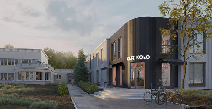 Pokaż zdjęcie: Dwukondygnacyjny jasny budynek z dużymi oknami. Środkowa zaokrąglona elewacja budynku w jest ciemnym kolorze. Na środku widnieje napis KAFE KOŁO.