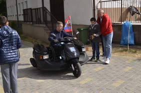 Pokaż zdjęcie: Osoba z niepełnosprawnością prezentuje pojazd przystosowany dla niepełnosprawnych. 