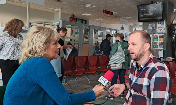 Kobieta z mikrofonem w dłoni z logo Radio PiK rozmawia z pracownikiem PFRON-u, siedzącym na wóżku inwalidzkim