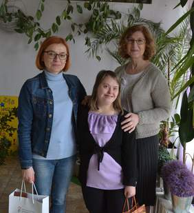 Pokaż zdjęcie: Na zdjęciu są 3 kobiety, dwie z nich trzymają w rękach torby z upominkami