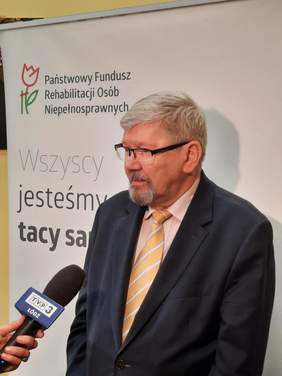 Pokaż zdjęcie: Dyrektor Łódzkiego Oddziału PFRON Władysław Skwarka udziela wywiadu dla telewizji TVP Łódż. W tle widać baner PFRON, na którym widnieje hasło: "Wszyscy jesteśmy tacy sami". 